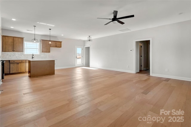 unfurnished living room with baseboards, a ceiling fan, light wood-type flooring, a sink, and recessed lighting