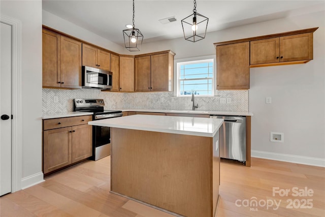 kitchen featuring light countertops, appliances with stainless steel finishes, a center island, and brown cabinets