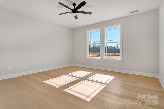 unfurnished room with a ceiling fan, light wood-type flooring, visible vents, and baseboards