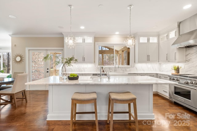 409 Running Horse Ln, Waxhaw, NC 28173 - kitchen with luxury stove, a sink, wall chimney exhaust hood, a breakfast bar, and decorative backsplash