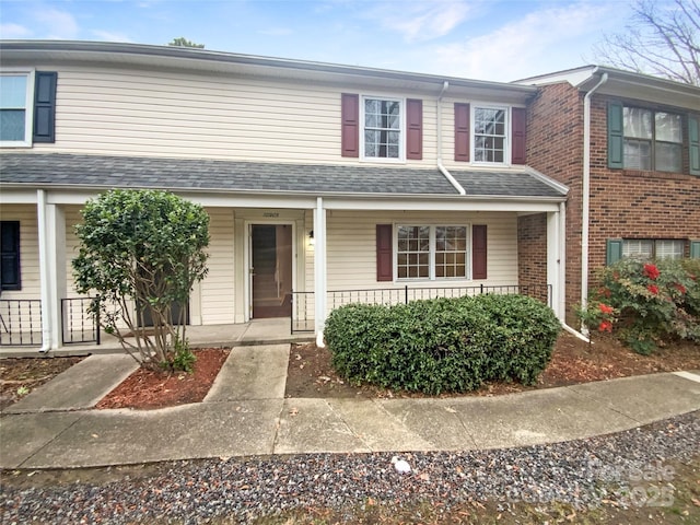 multi unit property featuring covered porch and roof with shingles