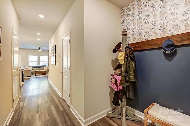 corridor with baseboards, wood finished floors, and recessed lighting