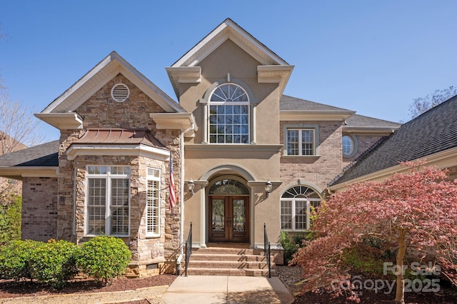 traditional-style home featuring roof with shingles, french doors, stone siding, and stucco siding