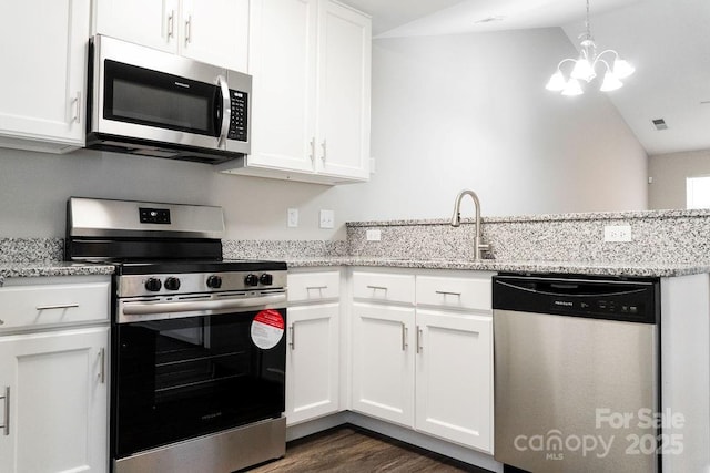 kitchen featuring appliances with stainless steel finishes, white cabinetry, vaulted ceiling, and light stone counters