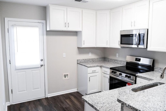 kitchen featuring dark wood-style flooring, a sink, white cabinetry, appliances with stainless steel finishes, and light stone countertops
