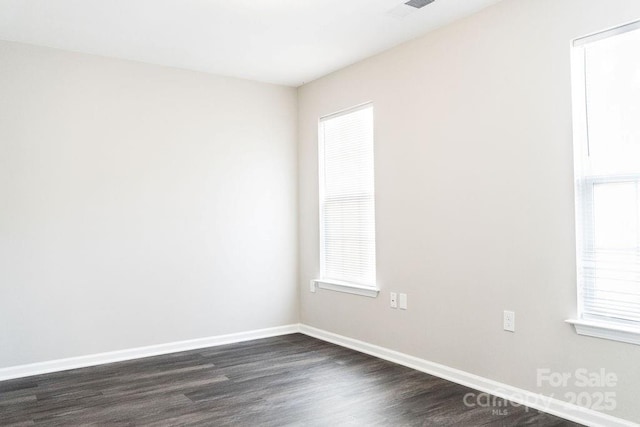 empty room with dark wood-style flooring, plenty of natural light, and baseboards