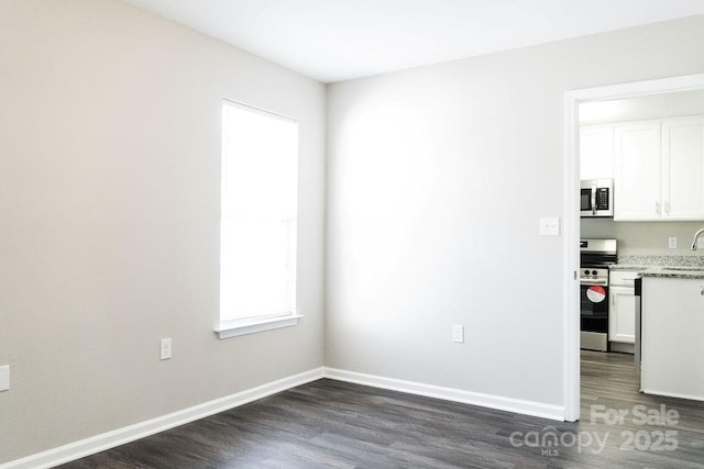 unfurnished dining area featuring a sink, baseboards, and dark wood-type flooring