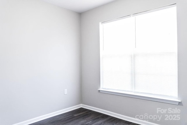 empty room with baseboards and dark wood finished floors