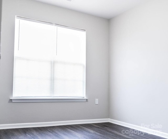 spare room featuring dark wood-style flooring and baseboards