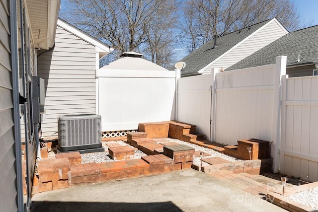 view of patio with a gate, fence, and central AC unit