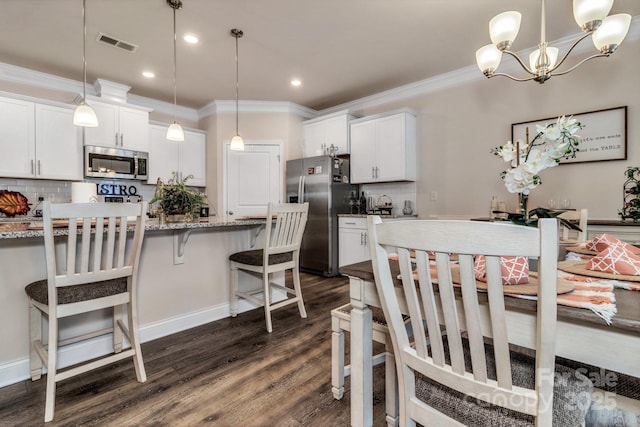 kitchen with white cabinetry, light stone counters, decorative light fixtures, and appliances with stainless steel finishes