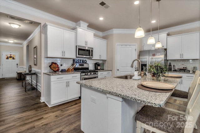 kitchen with appliances with stainless steel finishes, a kitchen island with sink, and white cabinets