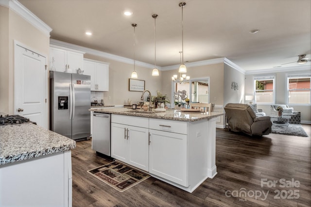 kitchen featuring appliances with stainless steel finishes, decorative light fixtures, sink, white cabinets, and a kitchen island with sink