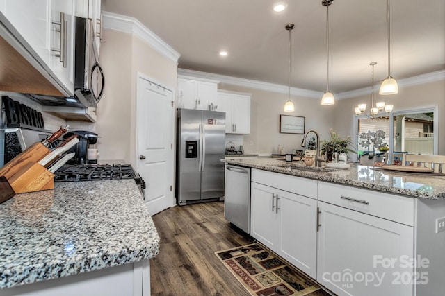 kitchen featuring white cabinetry, sink, hanging light fixtures, stainless steel appliances, and a center island with sink