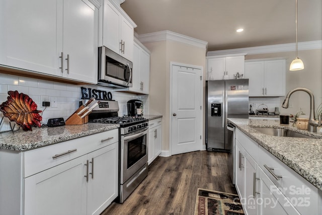 kitchen with appliances with stainless steel finishes, sink, white cabinets, ornamental molding, and light stone counters