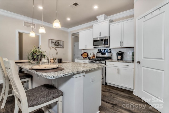 kitchen featuring white cabinetry, hanging light fixtures, a kitchen island with sink, and stainless steel appliances