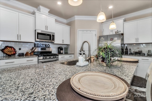 kitchen featuring appliances with stainless steel finishes, pendant lighting, white cabinetry, sink, and light stone countertops