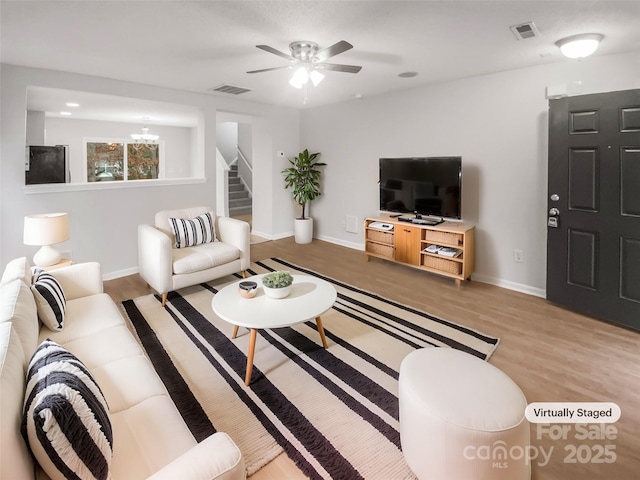 living room featuring stairs, visible vents, and wood finished floors