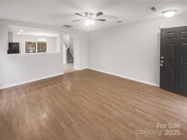 unfurnished room with baseboards, visible vents, stairway, and light wood finished floors