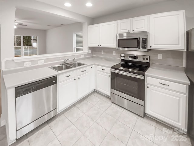 kitchen with light countertops, appliances with stainless steel finishes, white cabinetry, a sink, and a peninsula