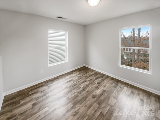 spare room featuring visible vents, baseboards, and wood finished floors