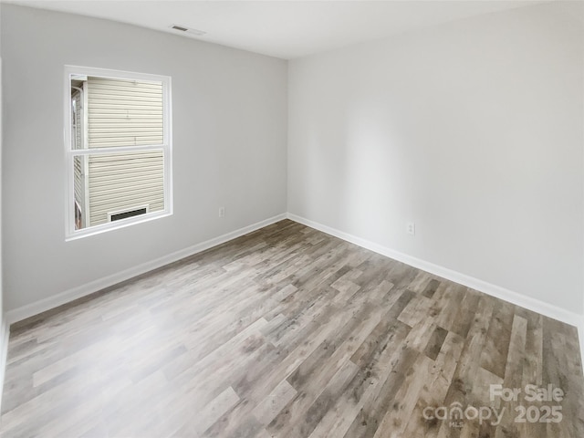 unfurnished room with light wood-type flooring, visible vents, and baseboards