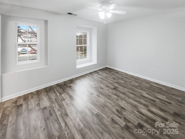 spare room with dark wood-style floors, ceiling fan, visible vents, and baseboards