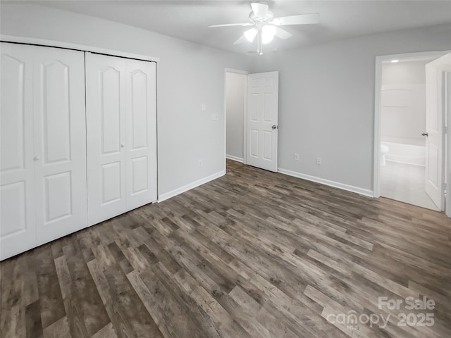 unfurnished bedroom featuring dark wood-style floors, a closet, connected bathroom, and baseboards