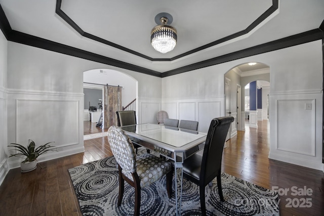 dining room featuring arched walkways, a decorative wall, dark wood finished floors, and a notable chandelier