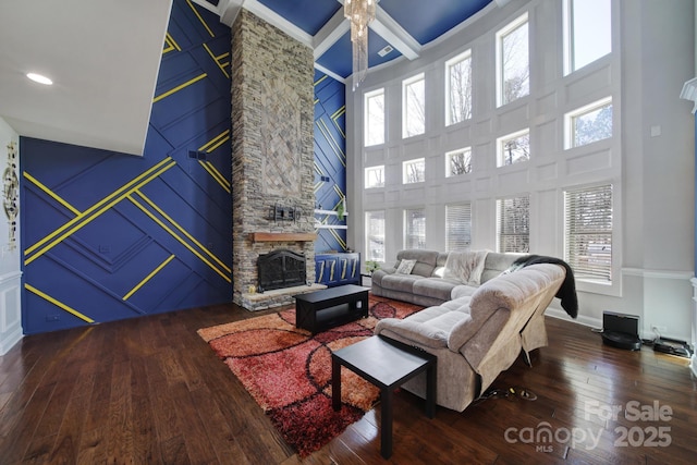 living area with hardwood / wood-style flooring, baseboards, a fireplace, and a high ceiling