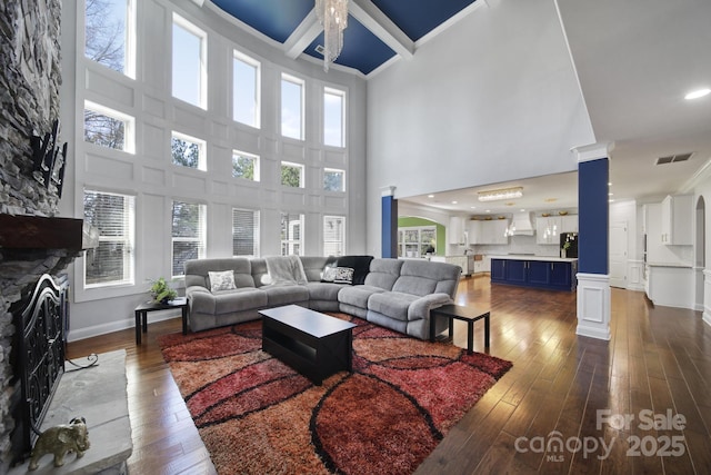 living room featuring ornamental molding, a fireplace, dark wood finished floors, and visible vents