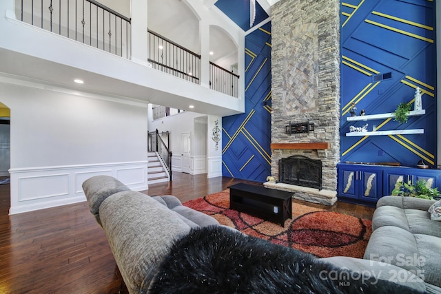 living area featuring dark wood-style flooring, stairs, a fireplace, a decorative wall, and recessed lighting