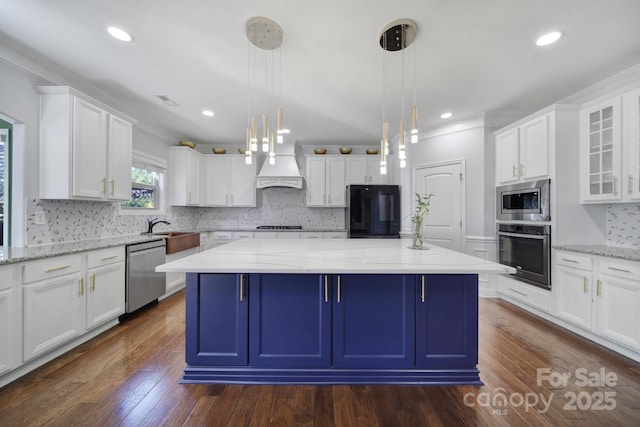 kitchen with appliances with stainless steel finishes, a center island, white cabinets, and pendant lighting