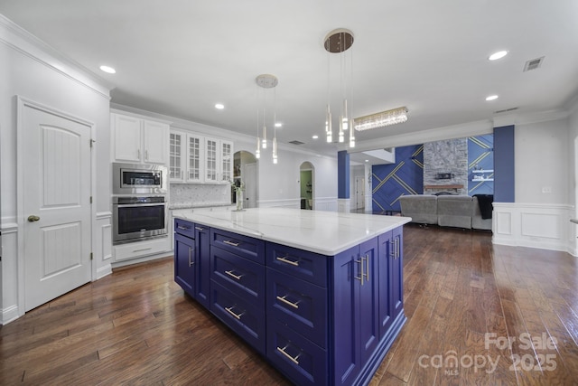 kitchen featuring glass insert cabinets, stainless steel appliances, white cabinetry, open floor plan, and decorative light fixtures