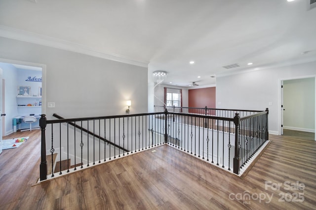 hall featuring wood finished floors, visible vents, an upstairs landing, baseboards, and ornamental molding