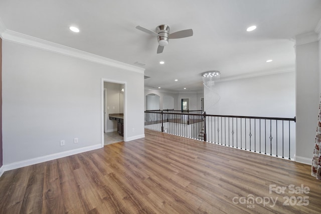 empty room with ornamental molding, recessed lighting, baseboards, and wood finished floors