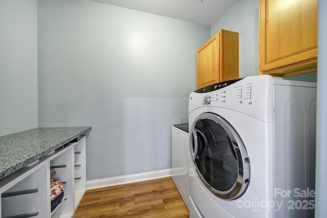 laundry area featuring dark wood-style flooring, cabinet space, baseboards, and washing machine and clothes dryer