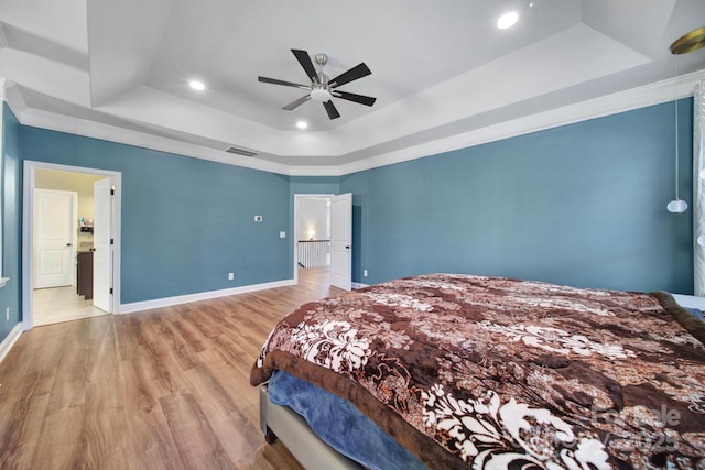 bedroom featuring light wood-style flooring, visible vents, a raised ceiling, and baseboards