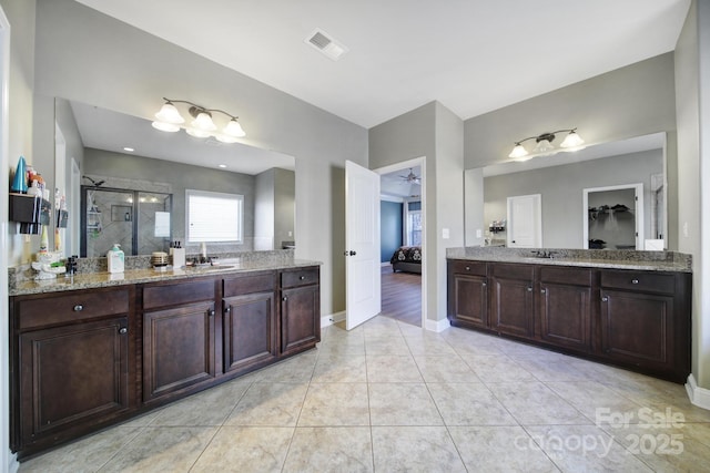 full bath with ensuite bathroom, a sink, two vanities, visible vents, and a stall shower