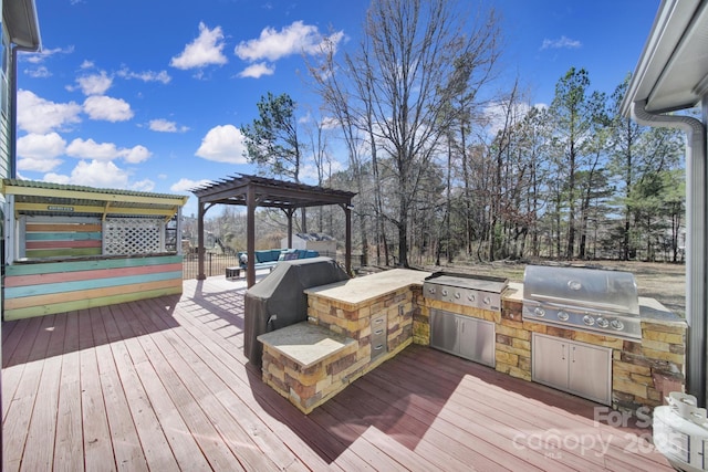 wooden terrace with exterior kitchen, area for grilling, and a pergola