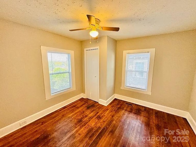 unfurnished bedroom with a textured ceiling, ceiling fan, dark hardwood / wood-style flooring, and a closet