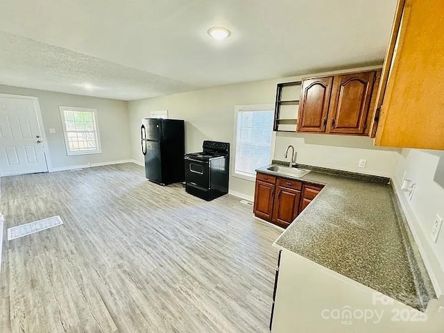 kitchen featuring light wood-type flooring, sink, black appliances, and a textured ceiling