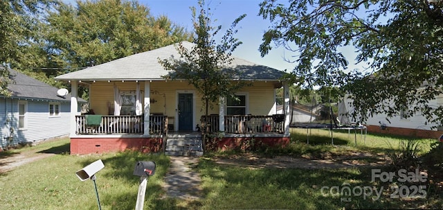 bungalow-style house with a trampoline, covered porch, and a front yard