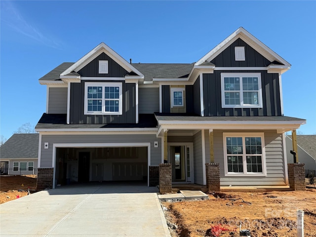 craftsman house featuring brick siding, board and batten siding, an attached garage, and driveway