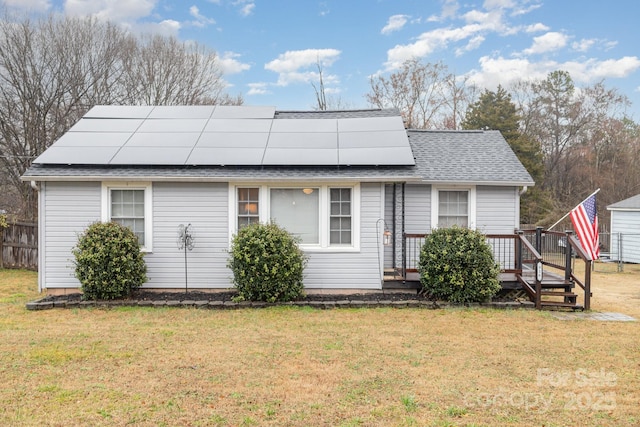 back of house featuring a lawn, a deck, and solar panels