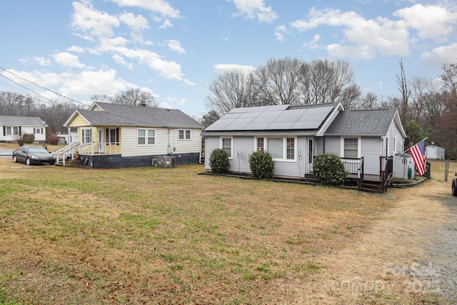 back of house with a deck, a lawn, and solar panels