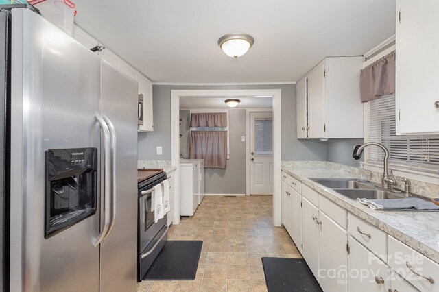 kitchen with white cabinetry, sink, stainless steel appliances, and washing machine and clothes dryer