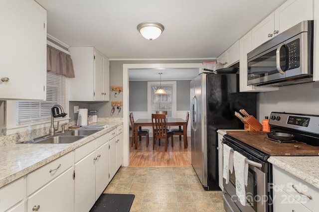 kitchen with white cabinetry, appliances with stainless steel finishes, sink, and pendant lighting