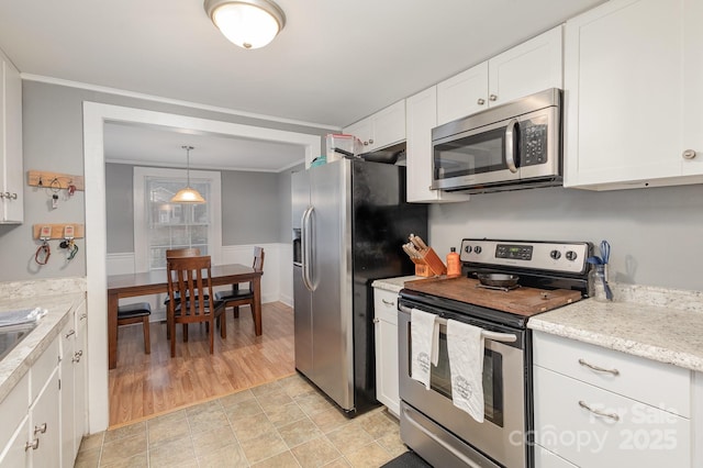 kitchen with pendant lighting, ornamental molding, white cabinets, and appliances with stainless steel finishes