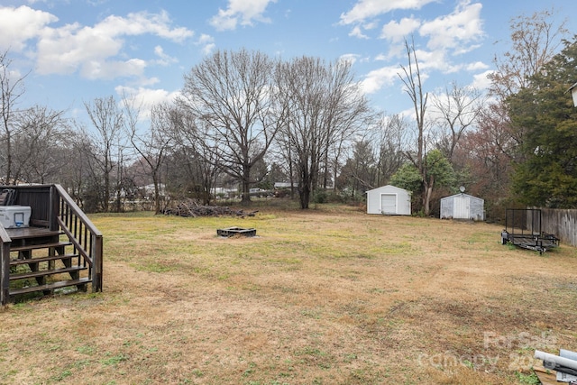 view of yard featuring a wooden deck, an outdoor fire pit, and a shed